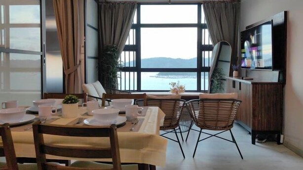 A dining area with a table set for two, a TV, and a view of the sea. - JESSELTON QUAYFULL SEA VIEWHIGH FLOORCOMFORT2BR4 PAX (Kota Kinabalu)