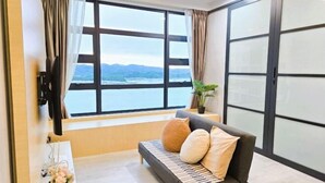 A room with a sofa, a view of the water, and a sliding door. - JESSELTON QUAYFULL SEA VIEWHIGH FLOORCOMFORT2BR4 PAX (Kota Kinabalu)