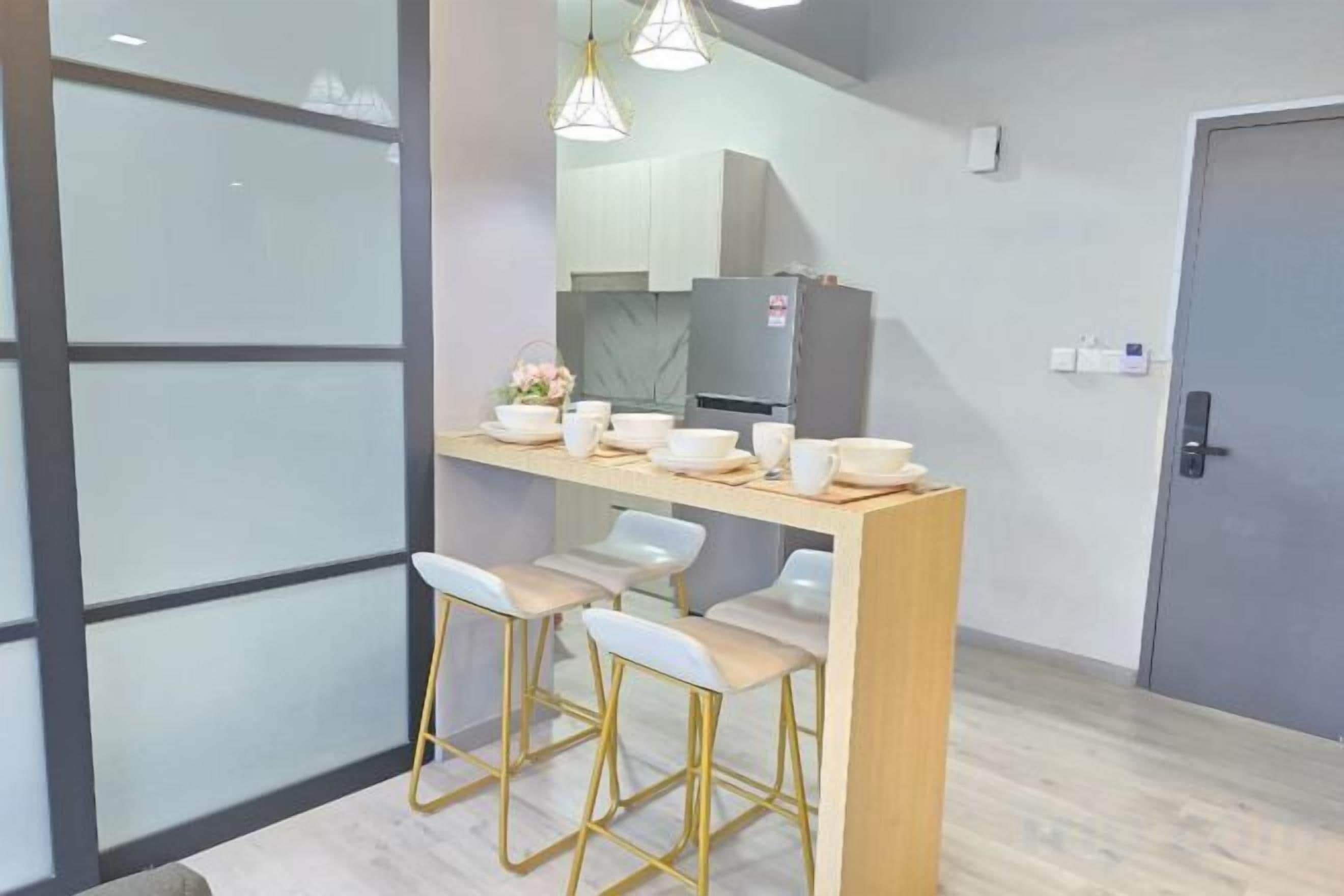 Uma cozinha moderna com área de bar, cadeiras brancas e iluminação pendente.