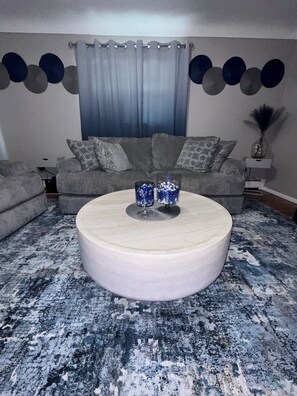 A living room with a round coffee table, grey sofa, patterned cushions, and a blue and white patterned rug. - Beautifully decorated space with private outdoor balcony. (Cincinnati)
