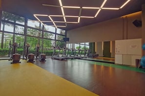 Ein Fitnessraum mit Laufbändern, Ergometer und einem grünen Boden.