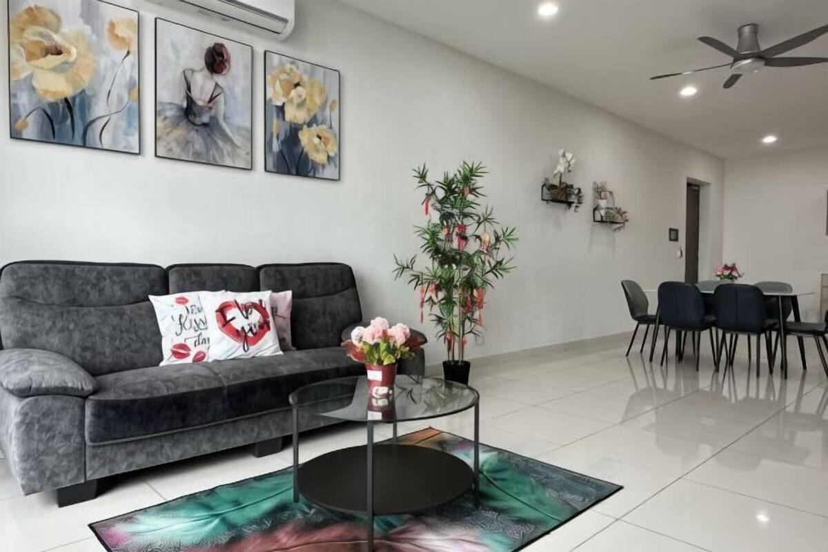 A modern living room with a grey sofa, a coffee table, and a dining area with a table and chairs.