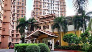 Un hôtel doté d’une cour intérieure, de palmiers et d’une voiture rouge garée devant l’entrée.