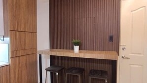 Un espace cuisine compact doté d’un plan de travail en bois, d’une petite plante en pot et de deux tabourets.