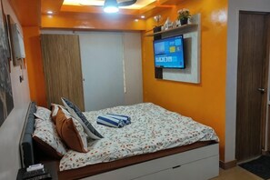 A bedroom with a bed, a television mounted on the wall, and a door. - Near Manila Airport, "Hotel Style" Studio Condo With Kitchen + Pool, 5G (Paranaque)