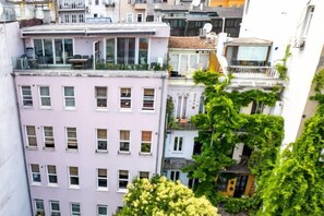 A multi-story building with a pink facade, multiple windows, and a balcony with greenery. - NOA - Tatar Beyi 18 (Istanbul)