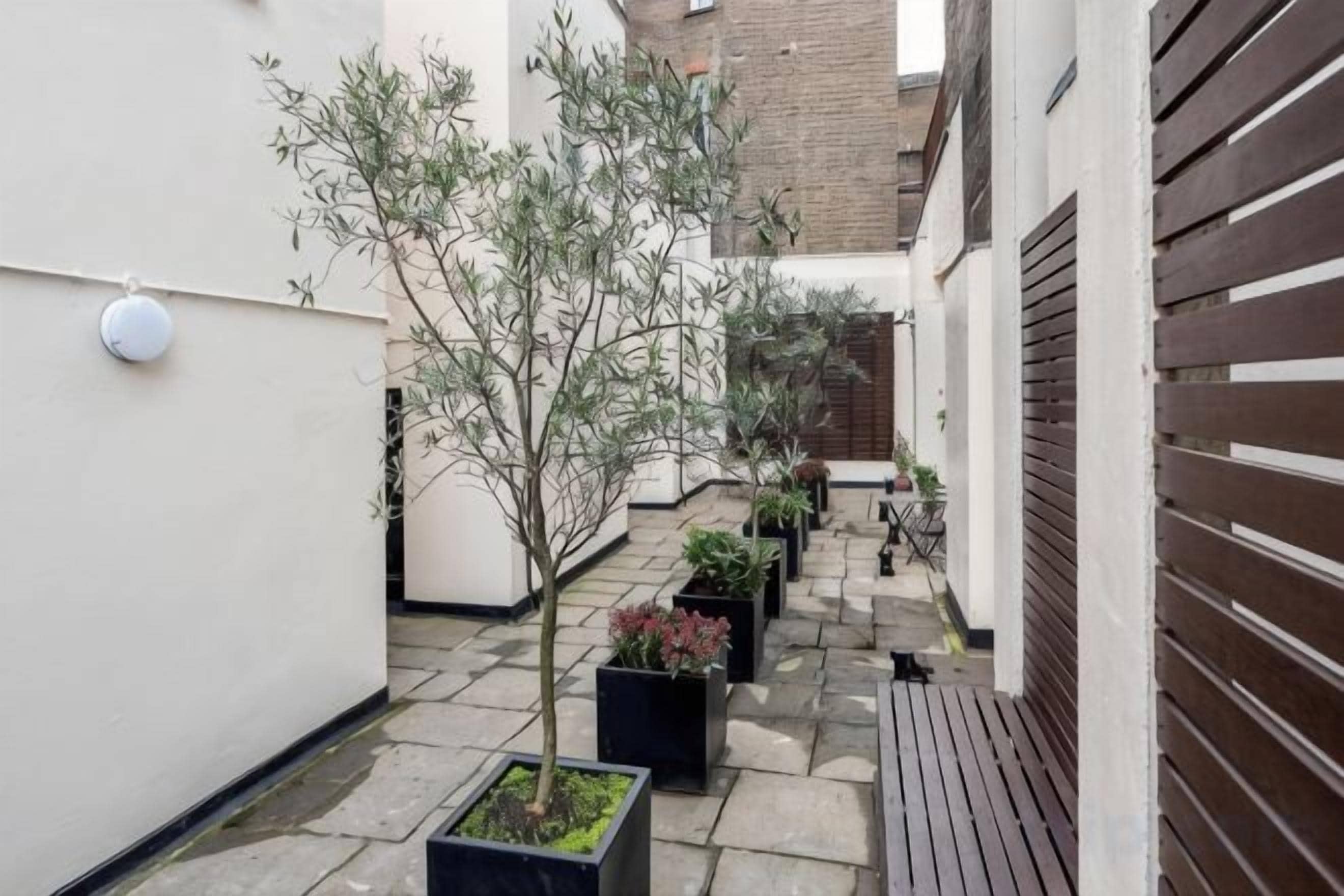 A narrow alleyway with potted plants and a wooden bench.
