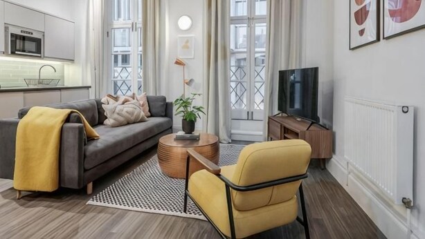 A modern living room with a sofa, armchair, coffee table, and a TV. - Kula London - Victoria (London)
