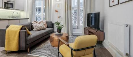 A modern living room with a sofa, armchair, coffee table, and a TV.