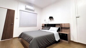 A bedroom with a bed, a bedside table, a wall-mounted lamp, a window with blinds, and an air conditioning unit. - uouRangnamHouse (Bangkok)