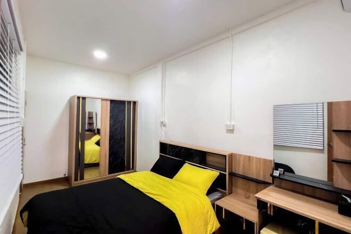 A modern bedroom with a bed, a mirror, a desk, and a wardrobe.
