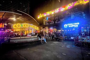 An outdoor dining area with neon signs, including 'COCO WALK' and 'CHILLING HOME.' - uouRangnamHouse (Bangkok)