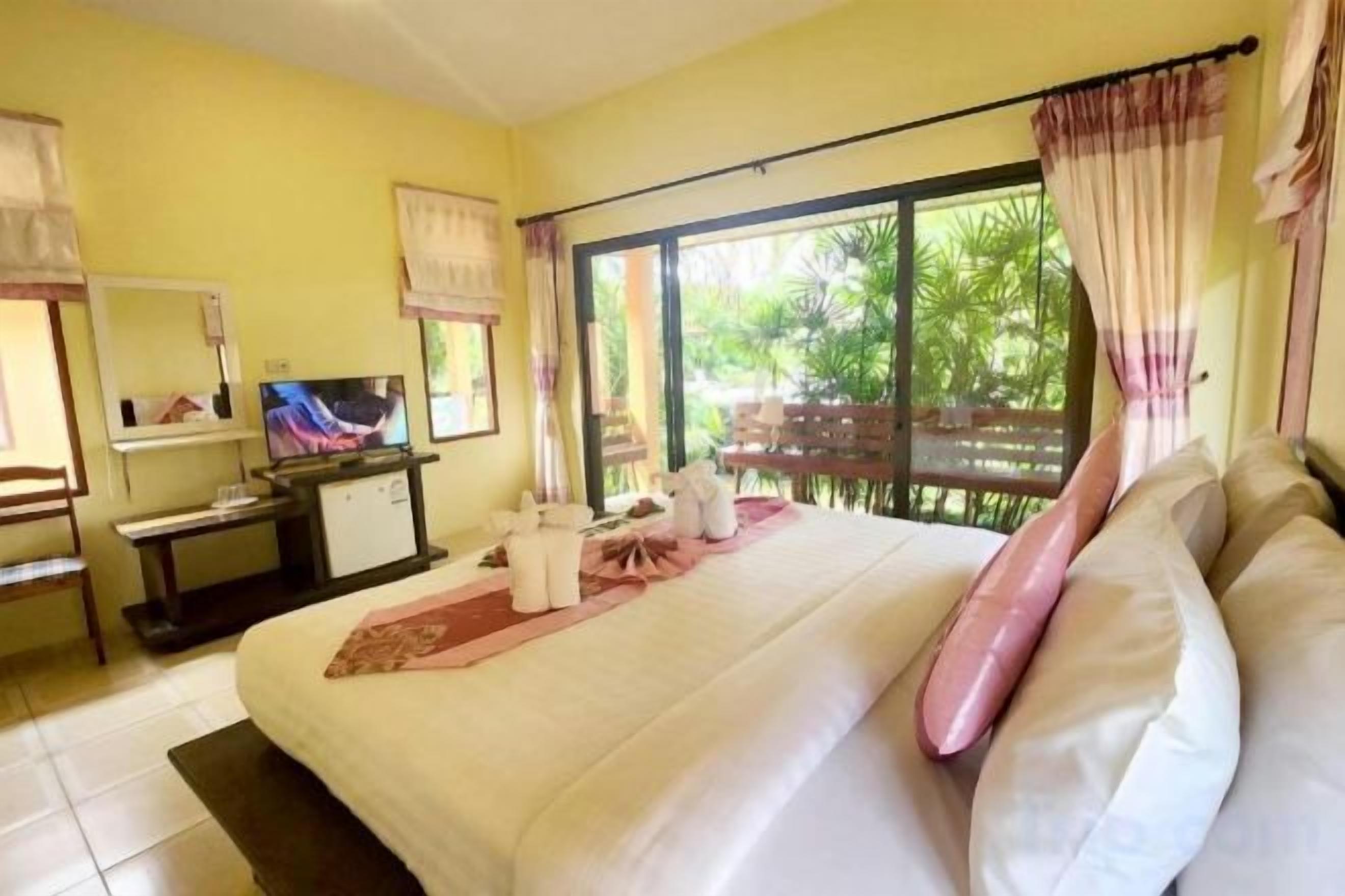 Una habitación de hotel con cama, escritorio con televisor y vista al exterior.