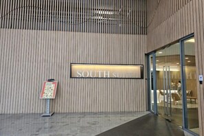 L’entrée d’un hôtel, avec une enseigne indiquant « SUITE SUD » et un comptoir d’accueil.