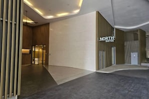 Un hall d’hôtel moderne avec un comptoir d’accueil, une enseigne indiquant « NORTH SUITES », et un mur au design incurvé.