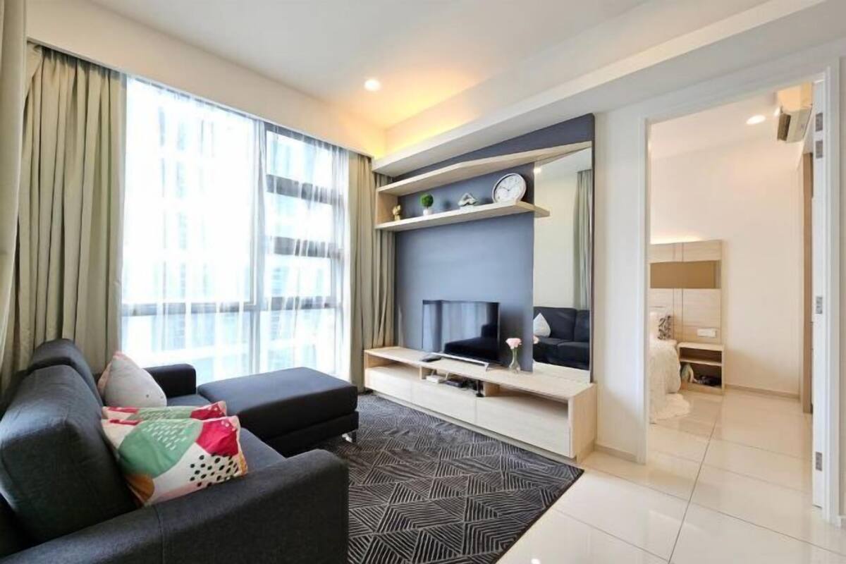 Een moderne woonkamer met een bank, een flatscreen televisie, een open haard en een groot raam met gordijnen.