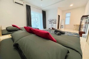A hotel room with a large bed, a desk, and a chair. There is a window with curtains, a door, and an air conditioning unit on the wall. - Spacious Home with Private Swimming Pool in Langkawi by Zervin (Langkawi)