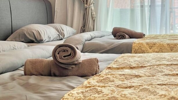 Ein Hotelzimmer mit einem Bett, einem gerollten Handtuch und einer gemusterten Bettdecke.
