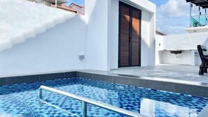 Ein Dachpool mit blauem Mosaikfliesenmuster, umgeben von weißen Wänden und in modernem Architekturstil.