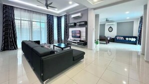 Ein modernes Wohnzimmer mit einer Couch, einem Fernseher, Deckenventilatoren und einem Essbereich.