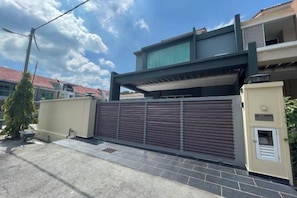 A modern residential building with a gated entrance, a covered walkway, and a visible electrical box. - Spacious Home with Private Swimming Pool in Langkawi by Zervin (Langkawi)