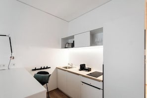 A compact kitchen with white cabinets, a sink, and a countertop. - The Place Herzogenaurach (Herzogenaurach)