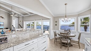 A spacious kitchen with a large island, white cabinetry, and a view of the ocean.