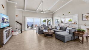 A spacious living room with a large gray sectional sofa, a coffee table, and a television on a wooden cabinet.