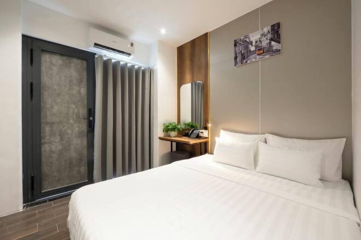 Ein modernes Hotelzimmer mit einem großen Bett, einem Nachttisch mit Lampe, einem Spiegel und einem Bild an der Wand.