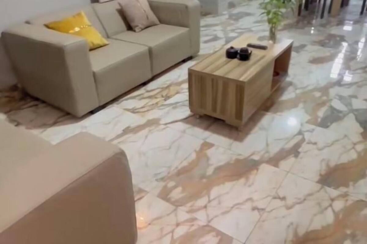 A modern living room with a beige sofa, a wooden coffee table, and a marble floor.
