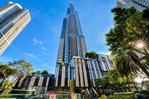 A high-rise building with a modern design, surrounded by other tall buildings and palm trees. - Cozy Haven Apartment - Vinhomes Central Park (Ho Chi Minh City)