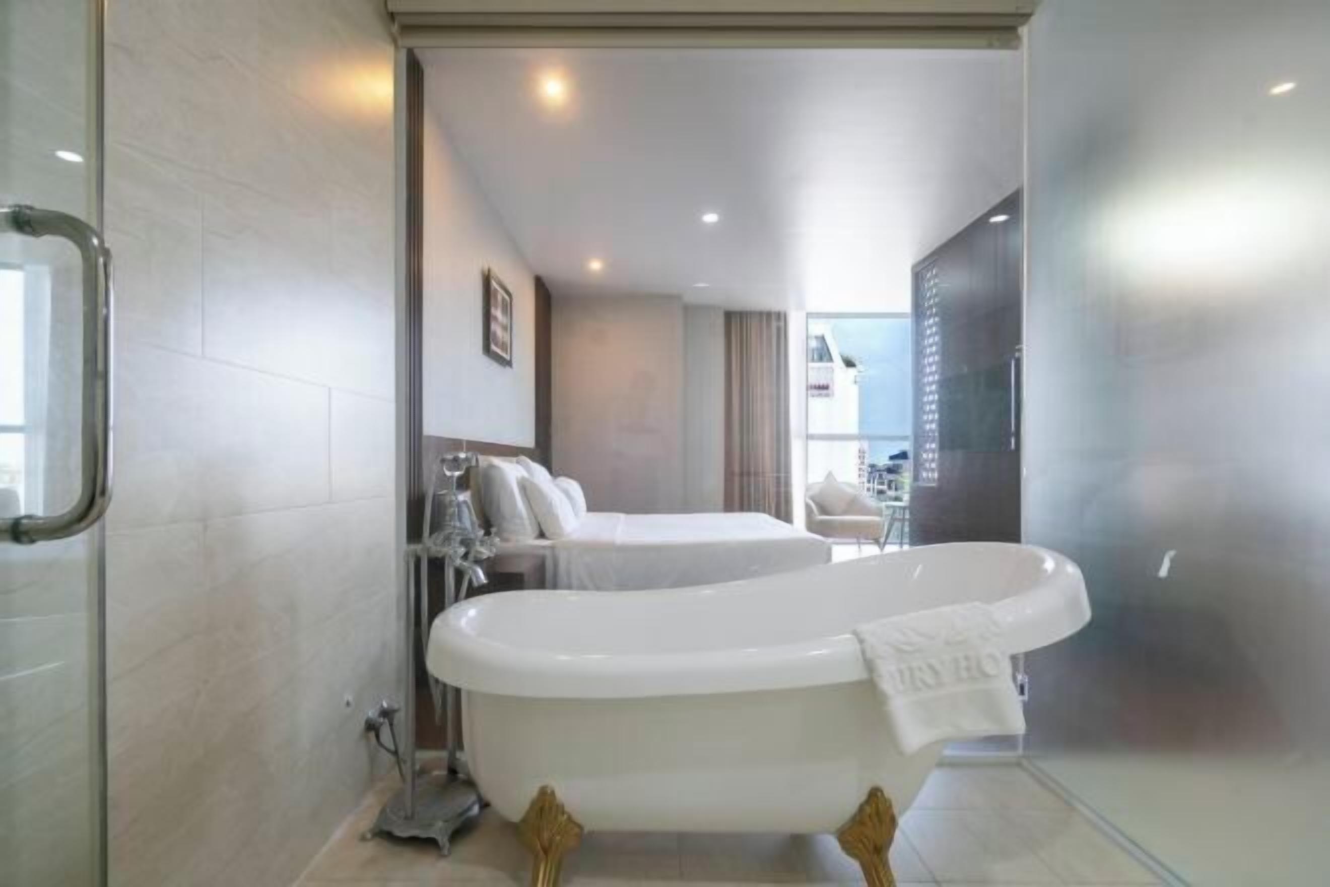A modern bathroom with a freestanding bathtub, a shower area, and a seating area with a sofa and armchairs.