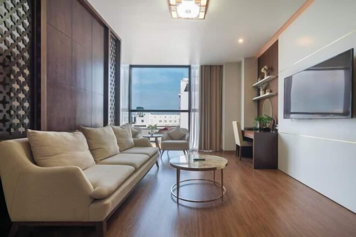 A modern living room with a sofa, a coffee table, and a TV mounted on the wall.