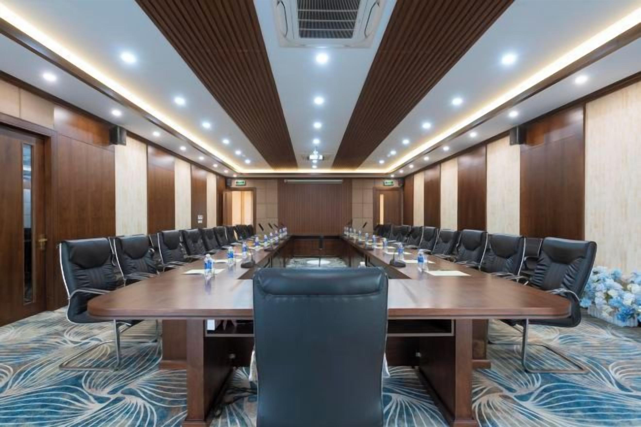 A conference room with a long table, chairs, and a carpeted floor.