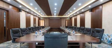 A conference room with a long table, chairs, and a carpeted floor.
