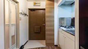 A narrow hallway leading to a door with a small electrical panel above it.