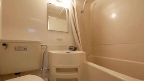 A small bathroom with a toilet, a sink, and a shower.