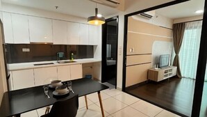 A modern kitchen with white cabinets, a black dining table, and a pendant light. - Almas Puteri Harbour Nusajaya Suite Room Exclusive Room 5 Min to Legoaland by HomeSpace (Iskandar Puteri)