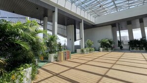 A spacious indoor area with a high ceiling, large windows, and potted plants. - Almas Puteri Harbour Nusajaya Suite Room Exclusive Room 5 Min to Legoaland by HomeSpace (Iskandar Puteri)