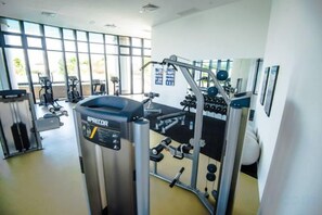 Un gimnasio con equipo de ejercicio, amplias ventanas y un interior impecable.
