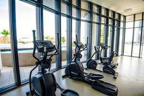 A gym with stationary bikes and treadmills, large windows, and a view of the outdoors. - Almas Puteri Harbour Nusajaya Suite Room Exclusive Room 5 Min to Legoaland by HomeSpace (Iskandar Puteri)