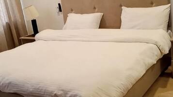Una cama con cabecera, una mesita de noche con lámpara y un espejo.