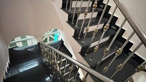 A multi-level staircase with black steps and a metal railing with decorative elements. - AoLai Hotel (Islamabad)