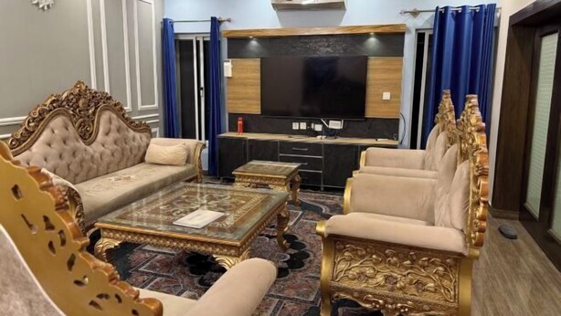 A luxurious living room with a large flat-screen TV, ornate furniture, and a patterned carpet. - AoLai Hotel (Islamabad)