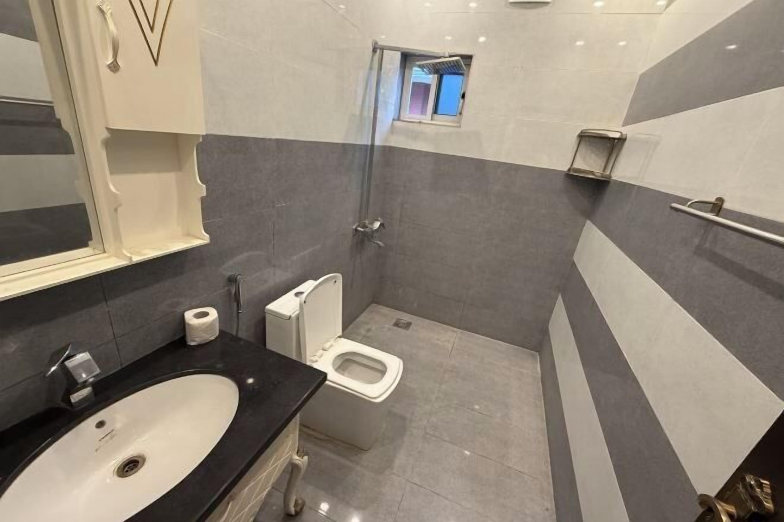 A modern bathroom with a black sink, white toilet, and a glass shower enclosure.