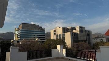 A rooftop terrace with a view of modern buildings and mountains in the distance.