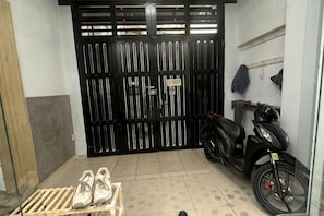 A closed black gate, a black scooter, and a pair of shoes on a wooden crate. - Aesthetic homes Bui Vien Street (Ho Chi Minh City)