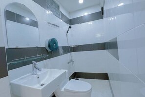A modern bathroom with a white sink, a toilet, and a shower area.