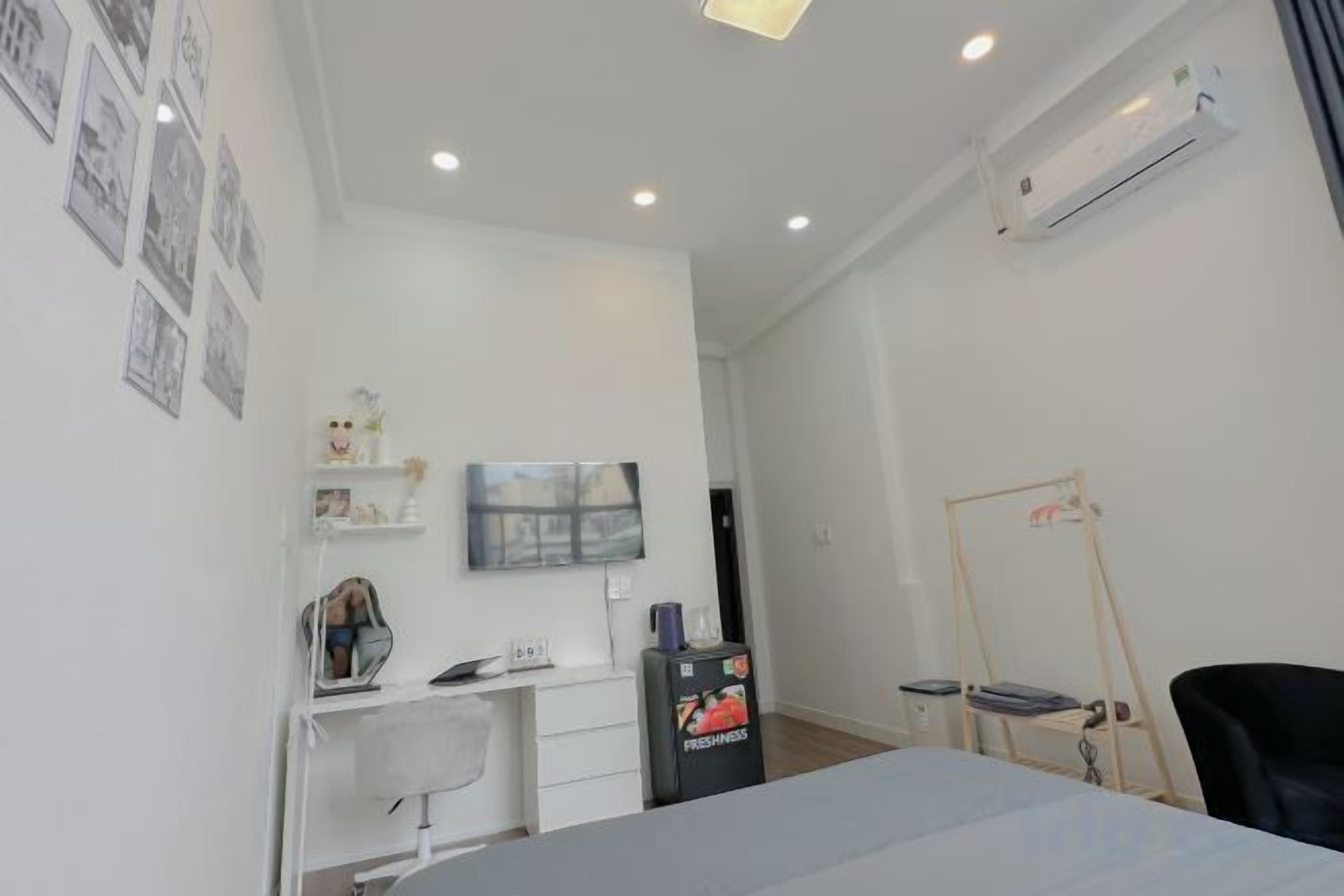 Habitación de hotel con cama, escritorio con silla, televisor y una pequeña mesa con otra silla.