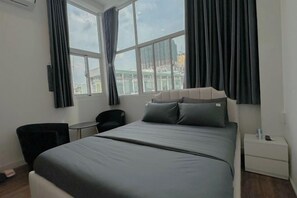 A hotel room with a bed, a chair, a small table, and a nightstand.